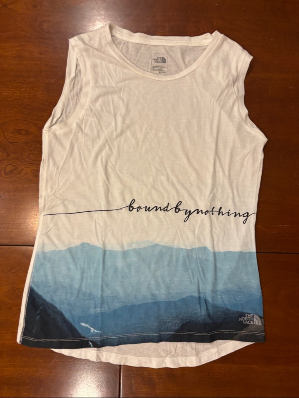 The North Face “Bound by Nothing@ White Tank with Blue Mountain Graphic